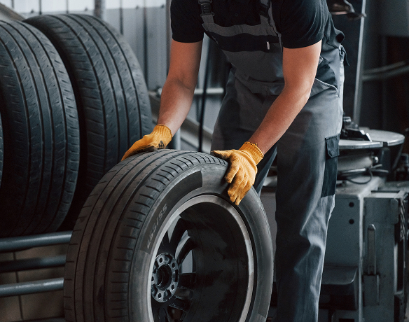 A Telle tire technician rolling a mounted tire off the rack in the shop.