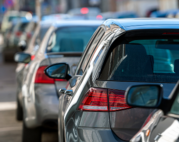 Several cars lined up in traffic in a busy city traffic jam.