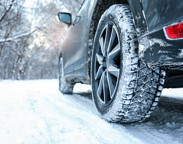 Close-up of winter tires on a vehicle covered in snow on a snowy road.