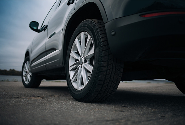 The view of a parked vehicle from the ground near the rear driver's side tire.