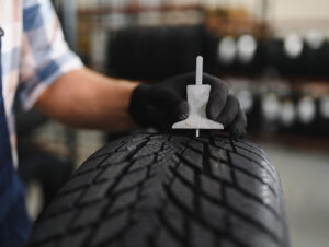 A Telle Tire mechanic using a specialized tool to measure the tread depth of a tire.