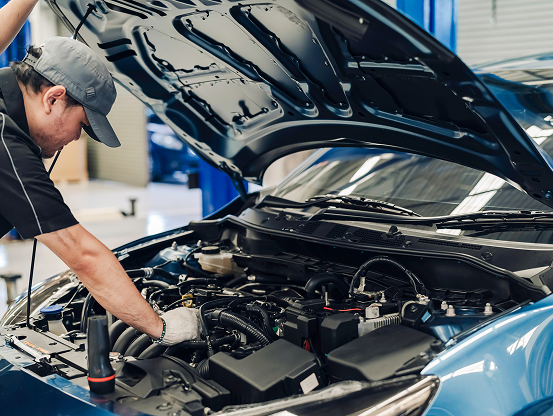 A Telle Tire automotive technician working on a car engine with the hood up.
