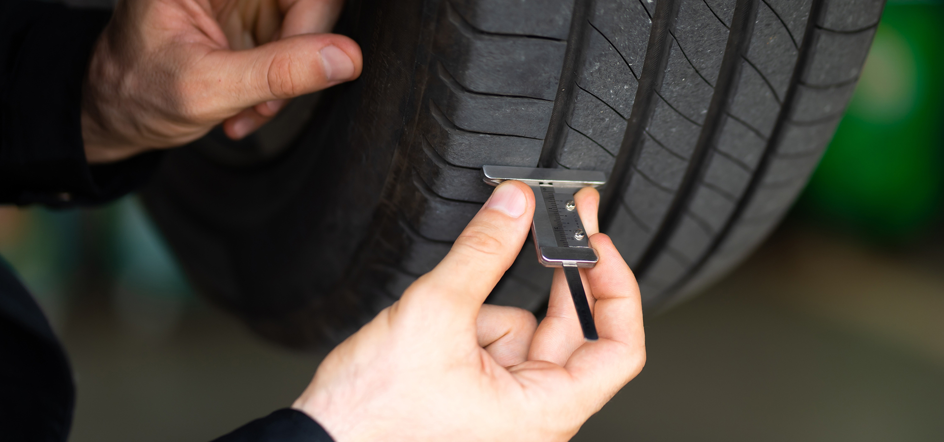 A Telle Tire technician using a specialized measuring tool to precisely measure the tread depth on a tire.