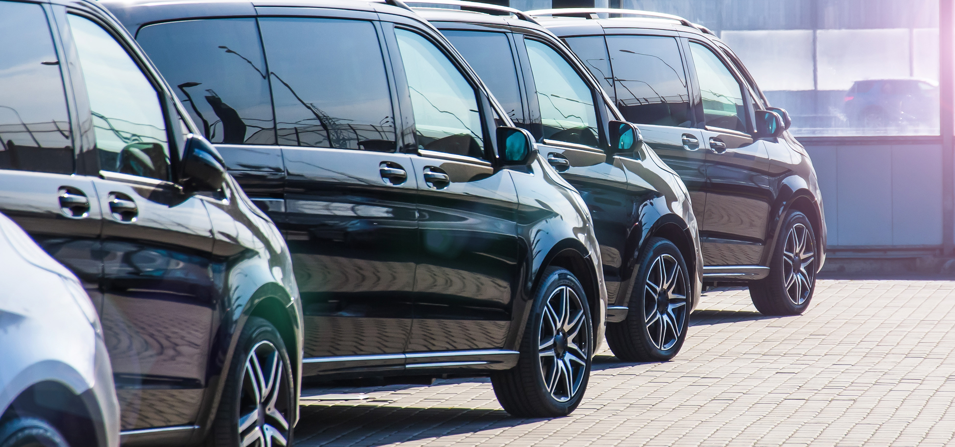 A lineup of commercial black minivans in a parking lot, ready for fleet service maintenance by Telle Tire.