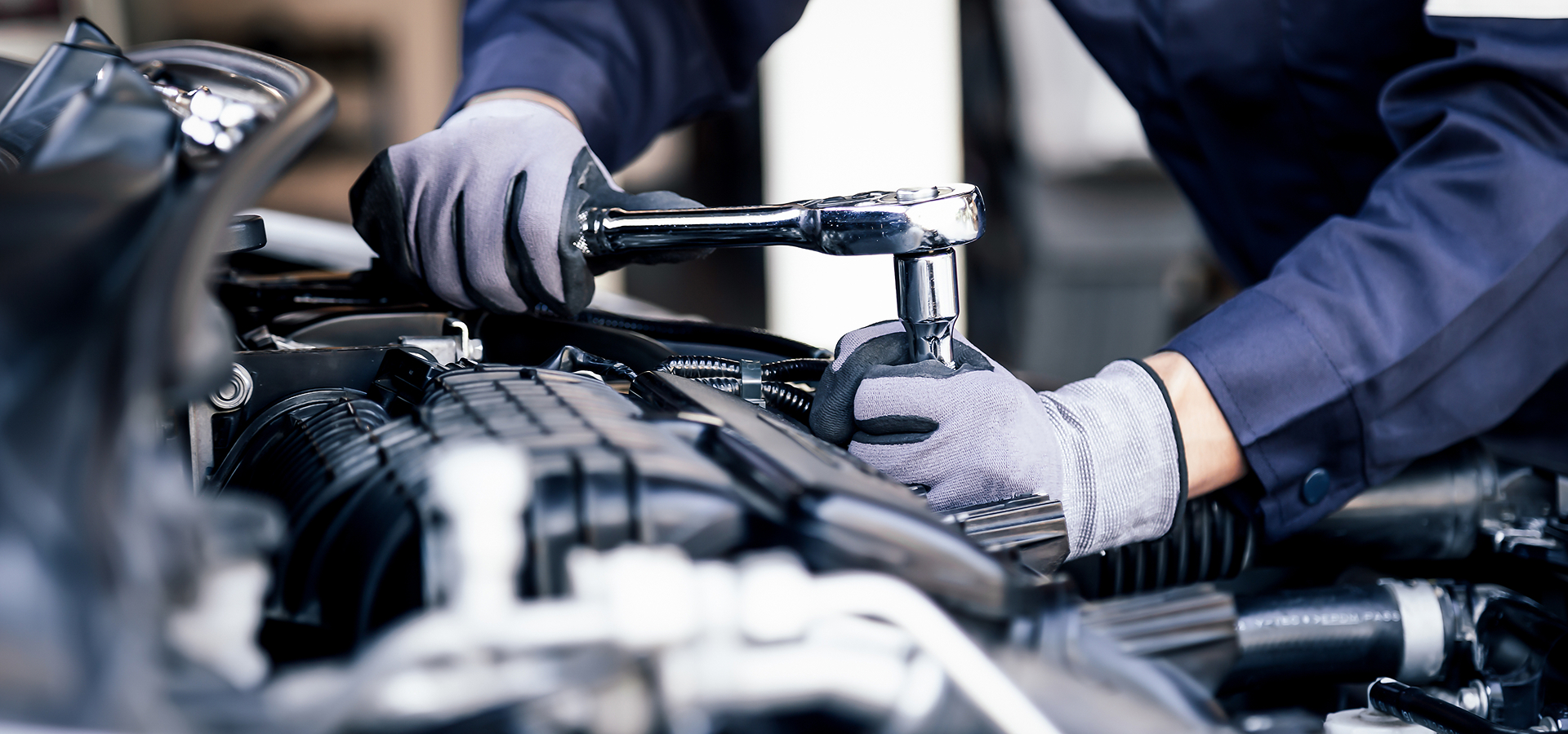A Telle Tire mechanic using a wrench while working on an engine component during routine automotive maintenance.