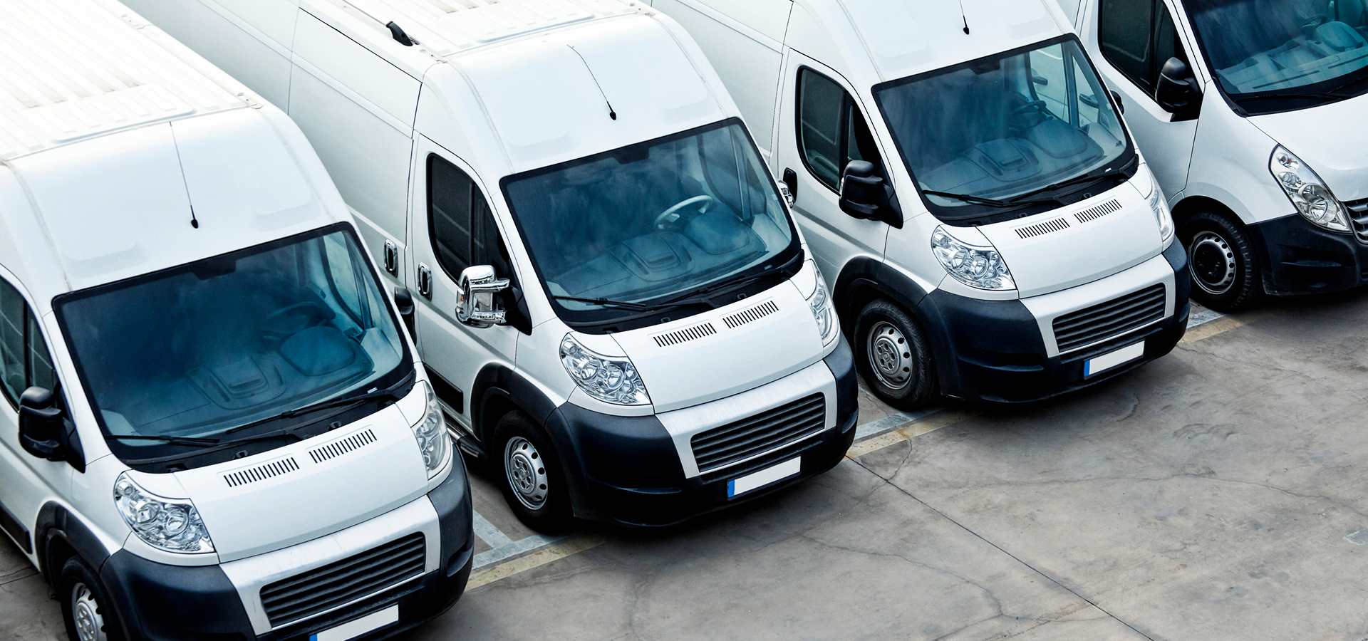 A lineup of white commercial vehicles in a parking lot, ready for fleet service maintenance by Telle Tire.