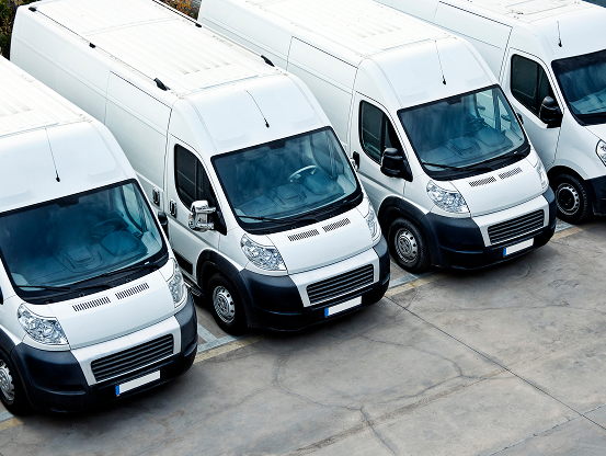 A lineup of white commercial vehicles in a parking lot, ready for fleet service maintenance by Telle Tire.