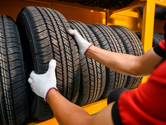 A Telle Tire technician, grabbing a brand new tire off the rack.