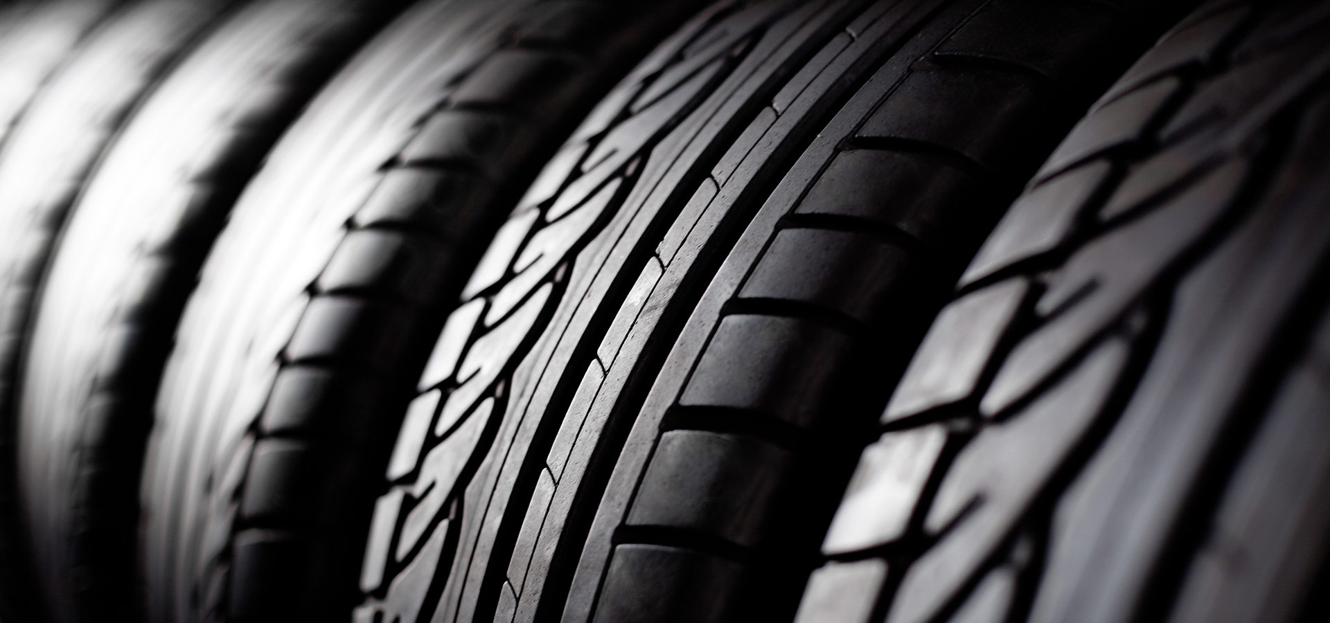 Close up of the tread on a row of tires lined together on the rack.