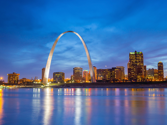 The St. Louis city skyline behind the Gateway Arch, taken from across the river just after sunset.