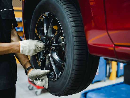 A Telle Tire technician hand-fastening the lug nuts on the wheel of a vehicle after new tire installation.