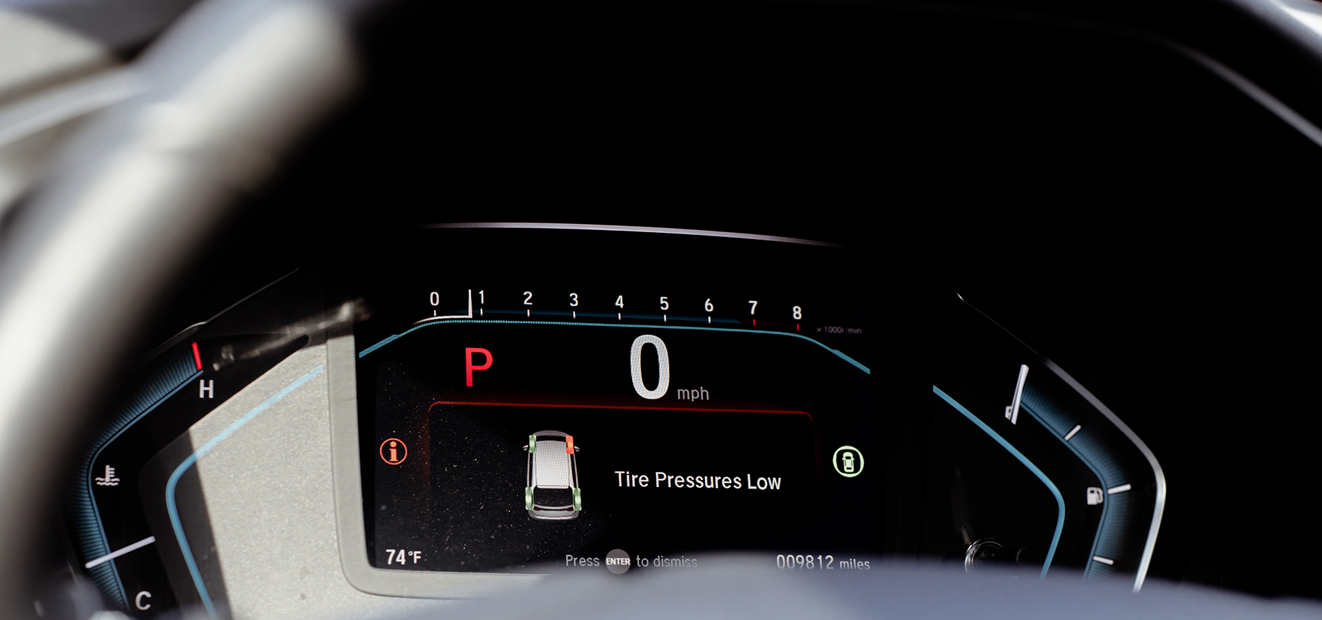 The digital dashboard gauges on a vehicle with a "Tire Pressure Low" warning indicated & passenger front tire highlighted red.