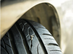 A view of a tire from the top with a small screw stuck inside a tread.