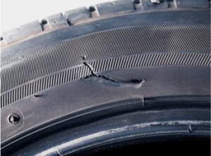 A closeup of a tire with a large gash in the sidewall.