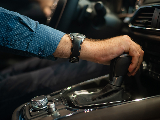 A man's hand on the shift knob of a vehicle.